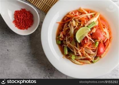Thai papaya salad in a white plate and dried shrimp, selective focus.