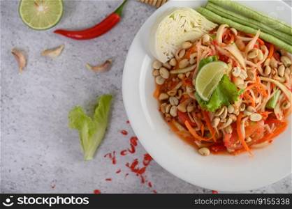 Thai papaya salad in a white plate with chili, lime, and garlic. Top view.