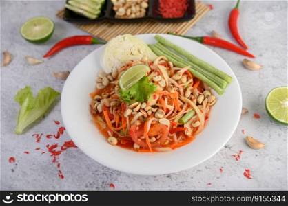 Thai papaya salad in a white plate with chili, lime, and garlic. Top view.