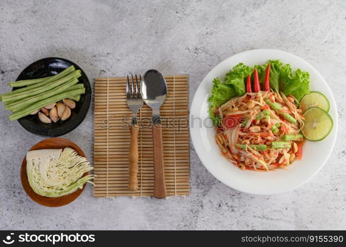 Thai papaya salad in a white plate with Sticky rice, Spoon, and fork.