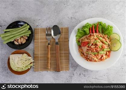 Thai papaya salad in a white plate with Sticky rice, Spoon, and fork.