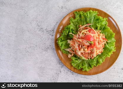 Thai papaya salad on salad in a wooden plate, Top view.