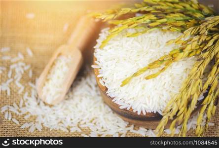 Thai rice white on bowl and sack background / raw jasmine rice grain with ear of paddy agricultural products for food in Asian