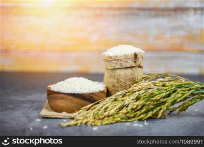 Thai rice white on bowl and the sack / raw jasmine rice grain with ear of paddy field agricultural products for food in Asian