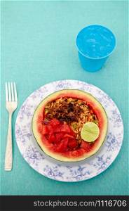 Thai spicy fried rice with crispy fried shallot serving in sweet watermelon. Thai Traditional way of eating fruit with hot spicy main course to balance the taste