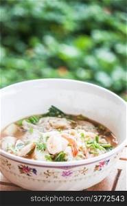 Thai spicy noodles soup with pork and shrimp on wood table