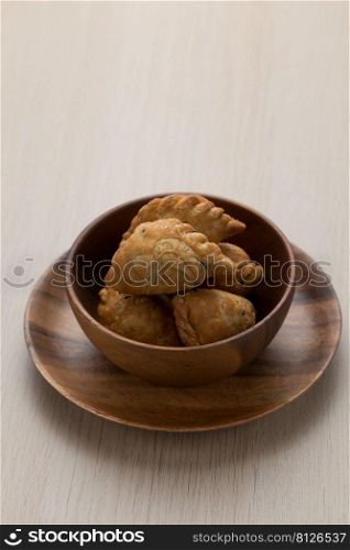 Thai-style curry puff in a dark brown wooden bowl.