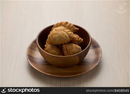 Thai-style curry puff in a dark brown wooden bowl.