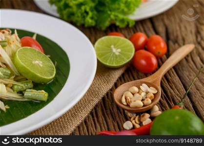 Thai style spicy food, Som Tum food concept, props decoration Garlic, lemon, peanuts, tomatoes, and shallots on wood table