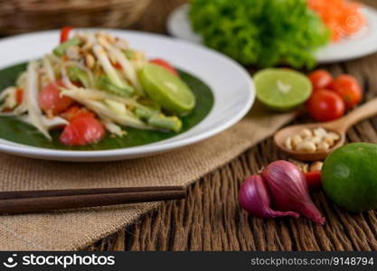 Thai style spicy food, Som Tum food concept, props decoration Garlic, lemon, peanuts, tomatoes, and shallots on wood table