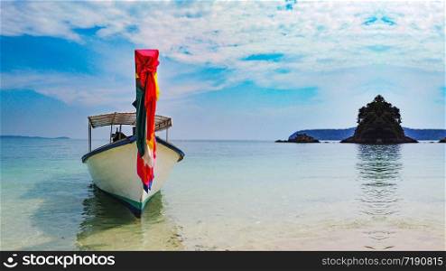 Thai traditionally boat which decorating with colorful cloth parking at island beach.