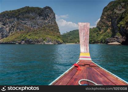Thai wooden head longtail boat heads toward the tropical Andaman shores at Thailand andaman