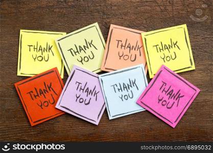 thank you abstract - handwriting on a set of colorful sticky notes against rustic wood