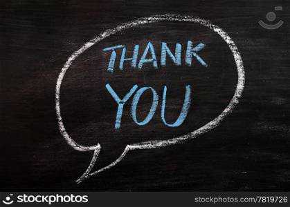Thank you written in a speech bubble with blue chalk on a smudged blackboard