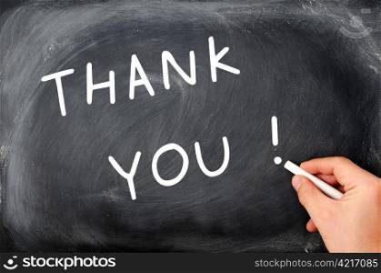 Thank you written on a blackboard, with a hand holding chalk,