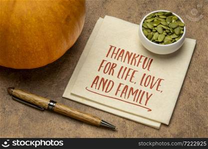 thankful for live,love, and family - Thanksgiving concept, handwriting on a napkin with a pumpkin and seeds