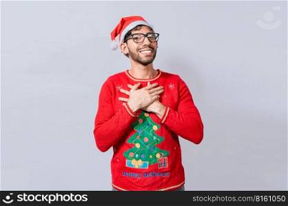 Thankful people in christmas clothes smiling with hands on chest. Man in christmas hat with sincere lovely smile feeling thankful, Smiling guy in christmas hat making thank you gesture