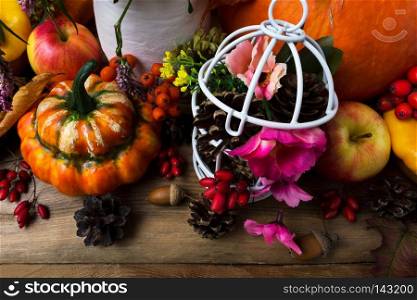 Thanksgiving arrangement with orange turban squash and white birdcage with cones, pink flowers