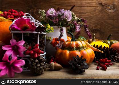 Thanksgiving arrangement with turban squash, rowan berries, clower, white birdcage, pine cones, pink and purple flowers