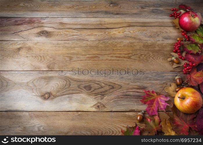 Thanksgiving background with apples, acorns, berries and fall le. Thanksgiving background with apples, acorns, berries and fall leaves on the old wooden background. Thanksgiving background with seasonal berries and fruits. Abundant harvest concept.