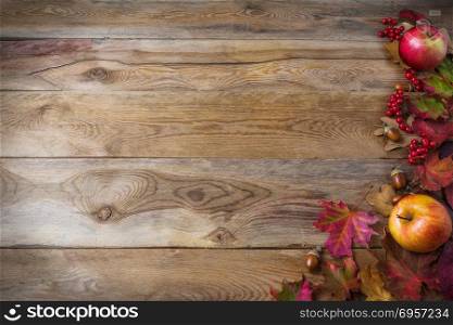 Thanksgiving background with apples, acorns, berries and fall le. Thanksgiving background with apples, acorns, berries and fall leaves on the old wooden background. Thanksgiving background with seasonal berries and fruits. Abundant harvest concept.