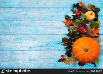Thanksgiving background with leaves and squash on blue wooden . Happy Thanksgiving greeting with squash, apples and autumn leaves on theright side of blue wooden table. Fall background with seasonal vegetables and fruits, copy space