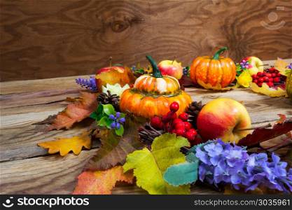 Thanksgiving background with leaves, ripe orange pumpkins, lilac. Thanksgiving background with colorful leaves, ripe orange pumpkins, apples, cones, lilac flowers and red berries door wreath, copy space