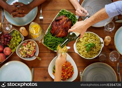 thanksgiving day, eating and leisure concept - group of people having dinner at table with food and drinking wine. group of people eating and drinking wine