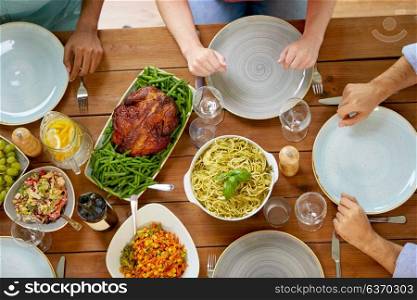 thanksgiving day, eating and leisure concept - group of people having roast chicken or turkey and pasta for dinner at table with food. group of people with chicken and pasta on table