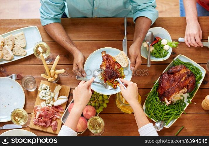 thanksgiving day, eating and leisure concept - group of people having roast chicken or turkey for dinner at table with food. group of people eating chicken for dinner