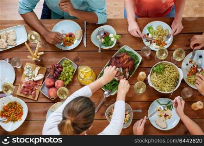 thanksgiving day, eating and leisure concept - group of people having roast chicken or turkey for dinner at table with food. group of people eating chicken for dinner