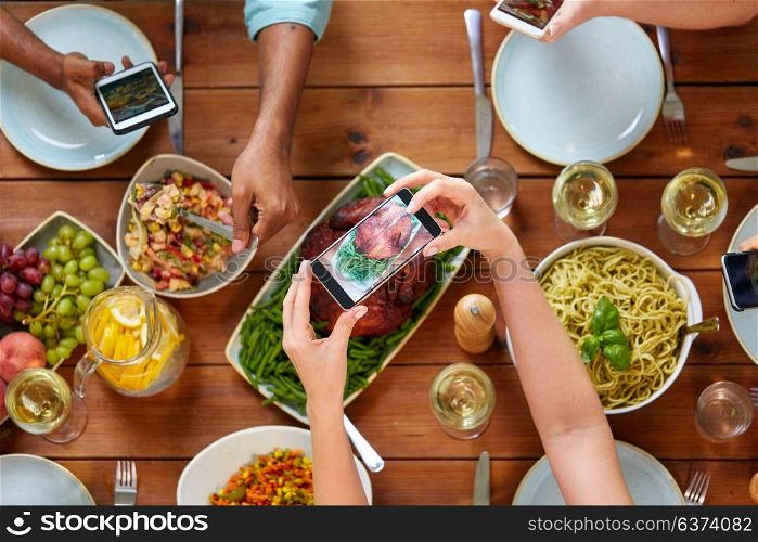 thanksgiving day, eating, people and technology concept - people with smartphones photographing food on table. people with smartphones photographing food