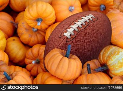 Thanksgiving Day football and autumn sports during harvest time with a holiday tournament ball in a pile of orange pumpkins as a concept for living a healthy lifestyle diet and exercise or fitness.