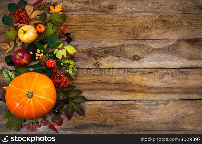 Thanksgiving decor with leaves and squash on wooden table. Happy Thanksgiving background with squash, apples and autumn leaves on the right side of rustic wooden table. Fall decor with seasonal vegetables and fruits, copy space