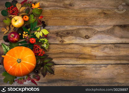 Thanksgiving decor with leaves and squash on wooden table. Happy Thanksgiving background with squash, apples and autumn leaves on the right side of rustic wooden table. Fall decor with seasonal vegetables and fruits, copy space