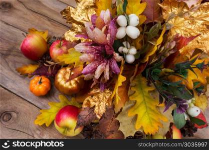 Thanksgiving decoration with silk flowers, snowberry and fall le. Thanksgiving decoration with silk flowers, apples, golden pumpkin, snowberry and fall leaves in vase, top view
