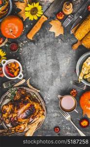 Thanksgiving dinner cooking preparation with various traditional dishes: turkey,pumpkin, corn,sauce and roasted harvest vegetables on rustic background, top view, frame