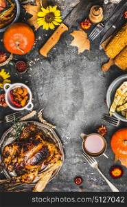 Thanksgiving dinner preparation. Roasted whole chicken or turkey ,sauce with grilled autumn vegetables,corn ,cutlery , decoration pumpkin, autumn leaves on rustic background, top view, frame.