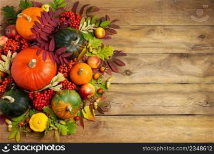 Thanksgiving green, orange pumpkins, rowan berry, leaves, yellow squash on the rustic wooden background, top view