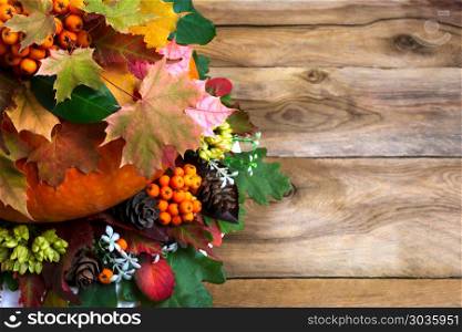 Thanksgiving greeting with maple leaves on old wooden table. Happy Thanksgiving greeting with autumn maple leaves on the left side of old wooden table. Fall background with seasonal vegetables and leaves, copy space