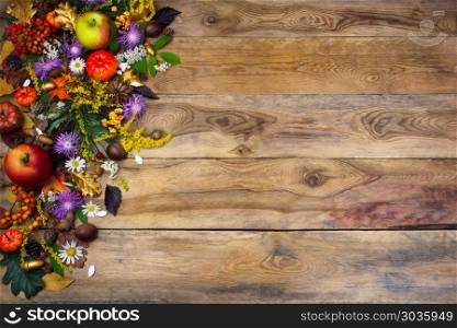Thanksgiving greeting with yellow and purple flowers . Thanksgiving greeting with pumpkin, apples, autumn leaves, yellow and purple flowers on the left side of old wooden table. Fall background with leaves and flowers