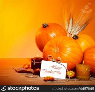 Thanksgiving holiday, pumpkin border still life decoration with candles and wheat over yellow studio light background, greeting card with text space, harvest concept