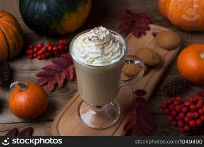 Thanksgiving homemade pumpkin spice coffee latte with whipped cream and cookies, fall leaves, rowan berries, fir cones