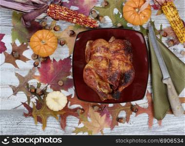 Thanksgiving meal with autumn acorns, corn, pumpkins and faded leaves on rustic table