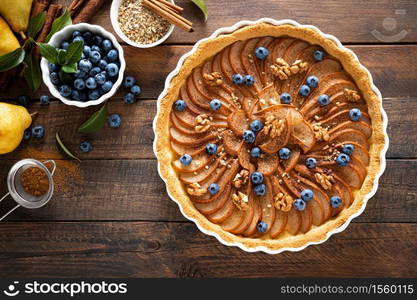 Thanksgiving pear tart, pie or cake with fresh pears and blueberry, cinnamon and walnuts