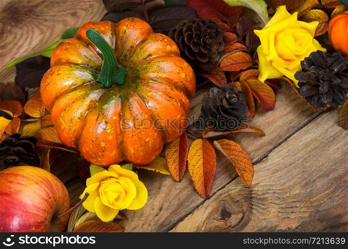Thanksgiving rustic arrangement with pumpkin, pine cones, apple and yellow roses