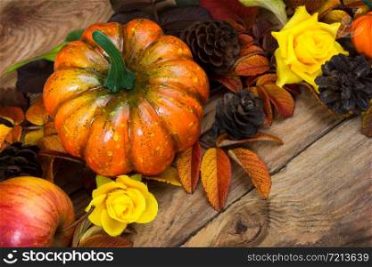Thanksgiving rustic arrangement with pumpkin, pine cones, apple and yellow roses