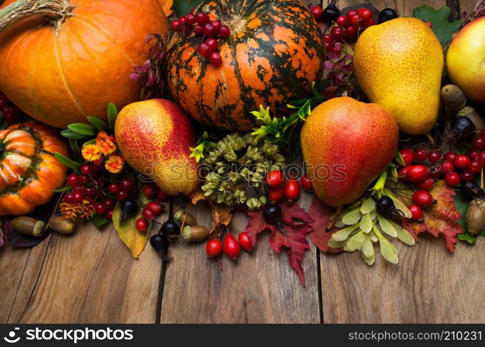 Thanksgiving rustic holiday arrangement with pumpkin, oak, pear, fall leaves and berry