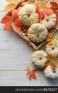 Thanksgiving season still life with small pumpkins and fall leaves over rustic wooden background