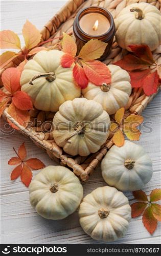 Thanksgiving season still life with small pumpkins and fall leaves over rustic wooden background